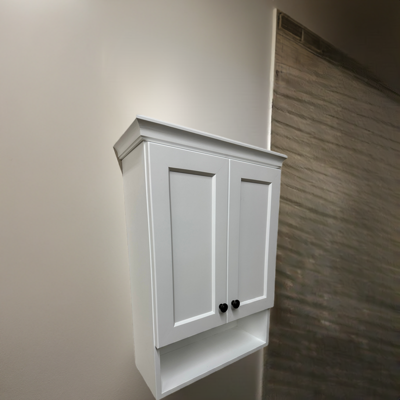 Manchester Over the toilet Shaker Vanity in white alder wood with crown molding, mounted on a neutral bathroom wall.