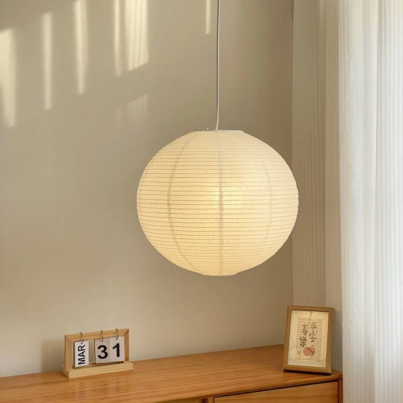 White Japanese style pendant light softly glowing in a minimalist living room, perfect for ambient lighting in home decor.