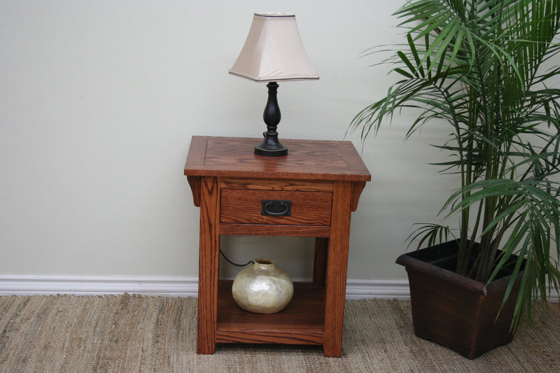 Mission O-M258 Oak End Table placed beside a plant and lamp, highlighting its handcrafted quality and functional drawer storage.