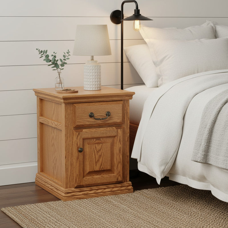 Traditional Oak End Table O-T250 used as a nightstand in a farmhouse bedroom, showing its drawer, cabinet, and solid oak frame.