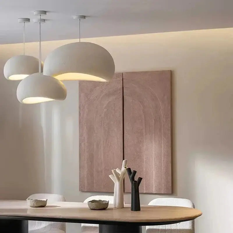 Three Wabi Sabi pendant lights in white above a round dining table. LED ceiling lamps offer stylish lighting for modern home interiors.